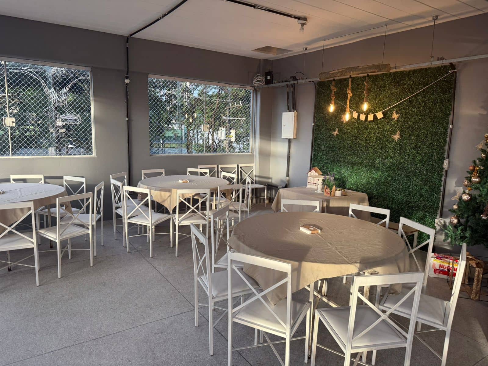 Salão de festas com muro verde e mesas decoradas